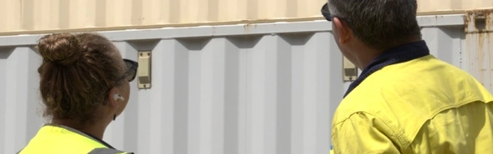Two people inspecting an ABC shipping container.