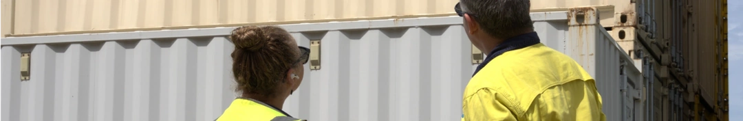 Two people inspecting an ABC shipping container.