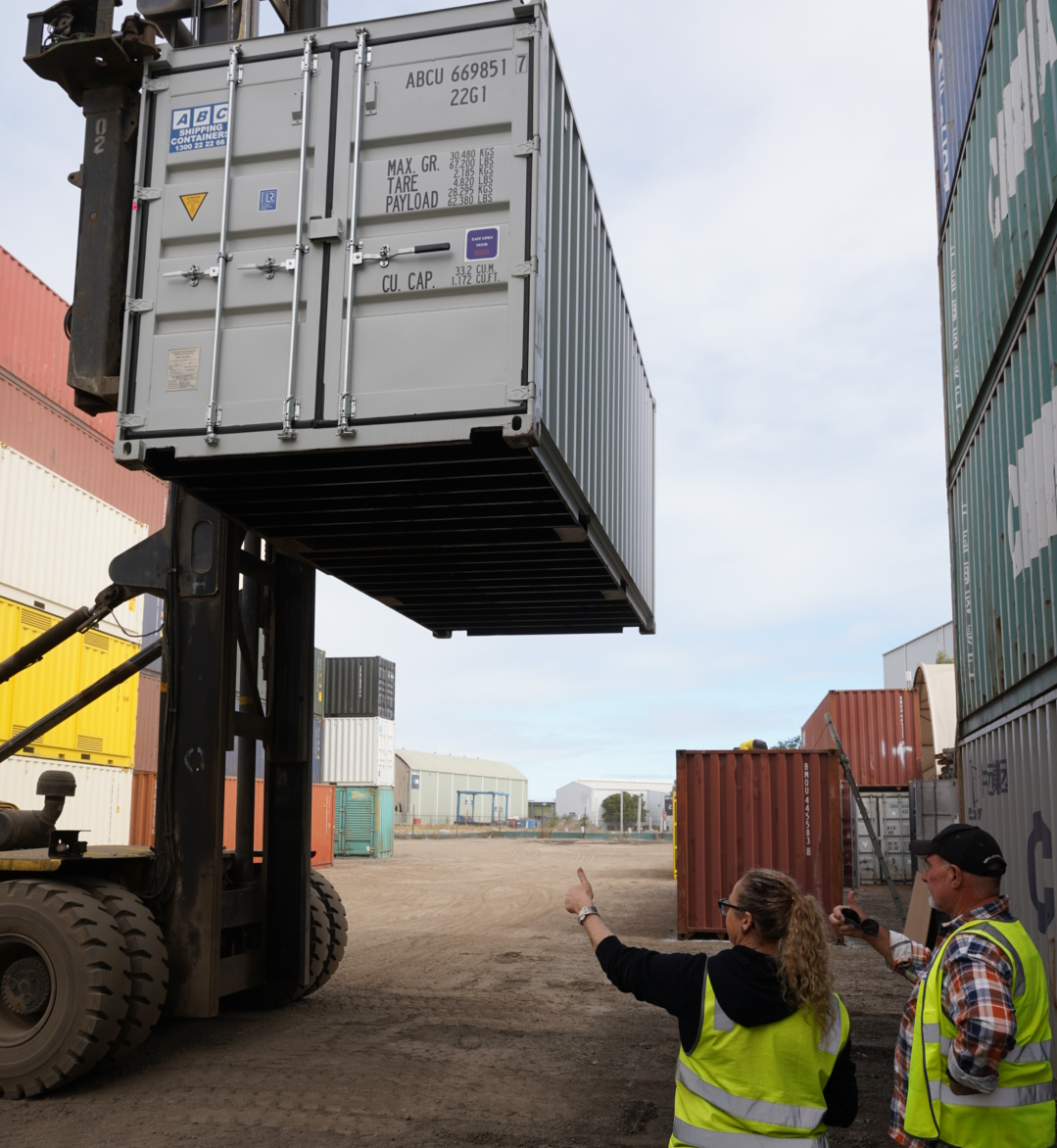 Two people inspecting the bottom of a shipping container